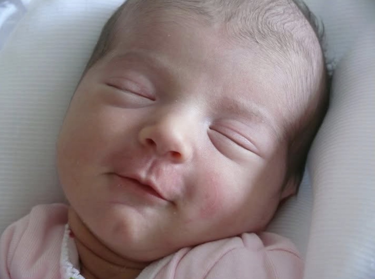Primer plano de un recién nacido dormido y sonriente