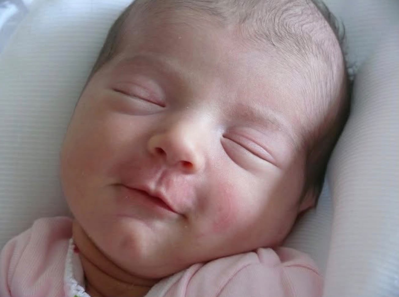 Primer plano de un recién nacido dormido con ropa rosada